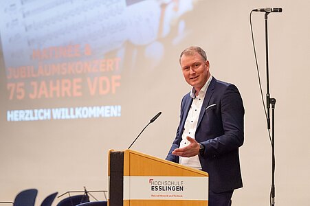 Baubürgermeister Sigel spricht an einem Rednerpult der Hochschule Esslingen, Präsentationsfolie im Hintergrund.
