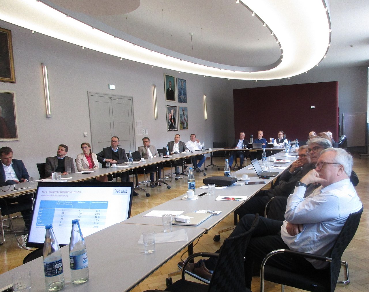 Rund zwanzig Teilnehmer der Vorstands- und Beiratssitzung sitzen an U-förmig angeordneten Tischen in einem großzügigen Konferenzraum.