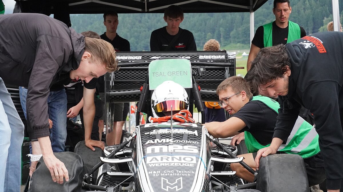 Mehrere Studenten nehmen technische Anpassungen am Formelwagen des Rennstalls der Hochschule Esslingen vor.